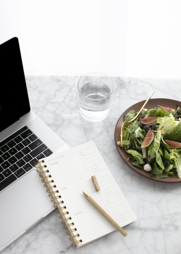 Computer, notebook and salad lunch. 